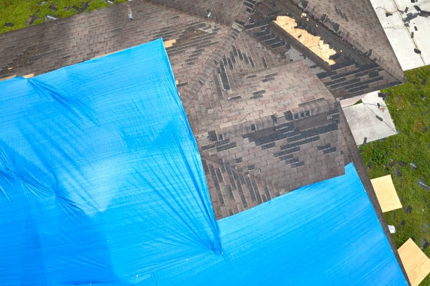 Roofing crew securing a roof tarp after severe weather damage