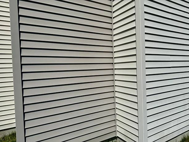 Contractor installing fiber cement siding panels with precision tools.