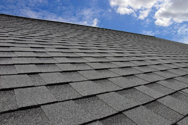 Roofer handling asphalt shingles during roof replacement using premium roofing materials