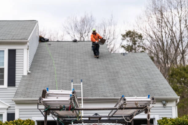 Roofer checking shingles and flashing during a routine roof inspection