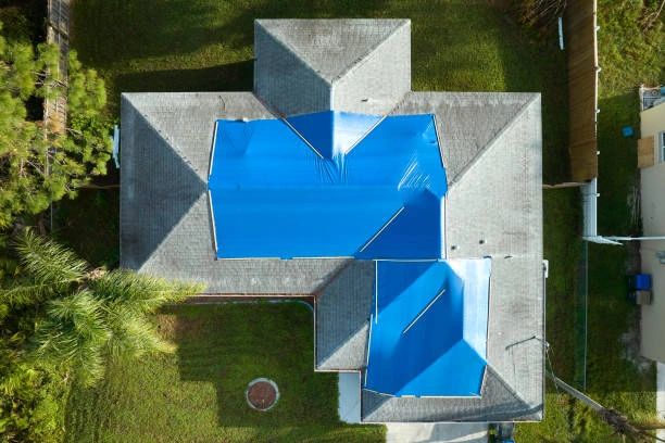 Blue roof tarp covering exposed section of a damaged residential roof