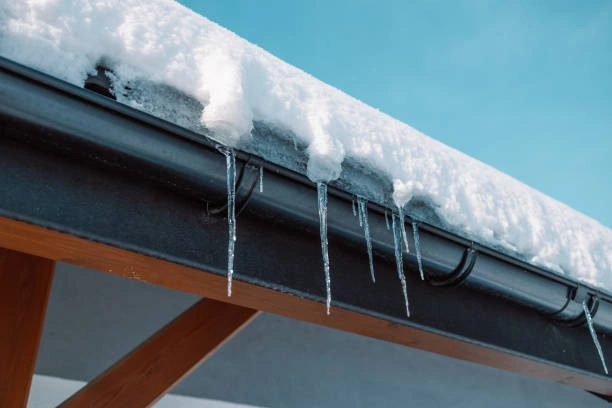 Roof edge with heavy ice buildup before professional ice dam removal