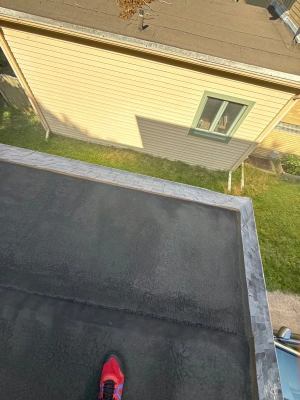 Professional roofing contractor repairing shingles on a residential roof to stop a water leak.