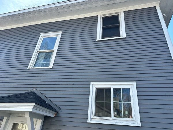Homeowner inspecting roof and siding for seasonal maintenance to prevent costly repairs.