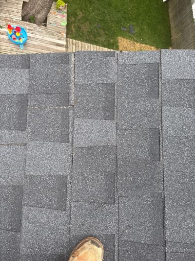 Close-up of asphalt shingles showing granule loss and bald spots near a gutter, illustrating normal wear versus warning signs of roof deterioration.
