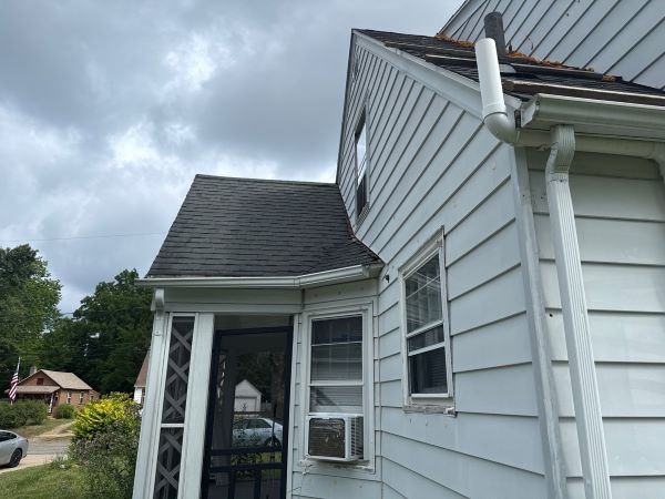 Gutter overflow causes showing water spilling over clogged gutters and downspout during heavy rain