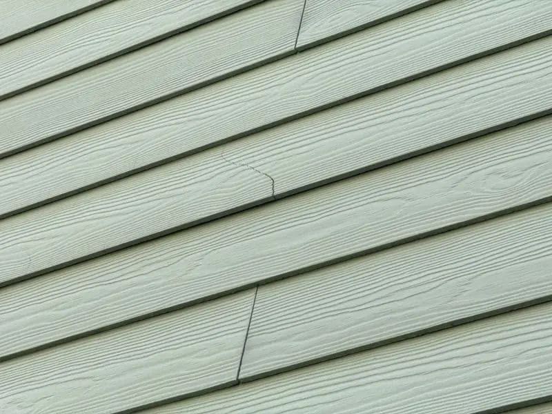 Siding corners crack on exterior home trim, showing visible damage and separation along the corner siding panel.